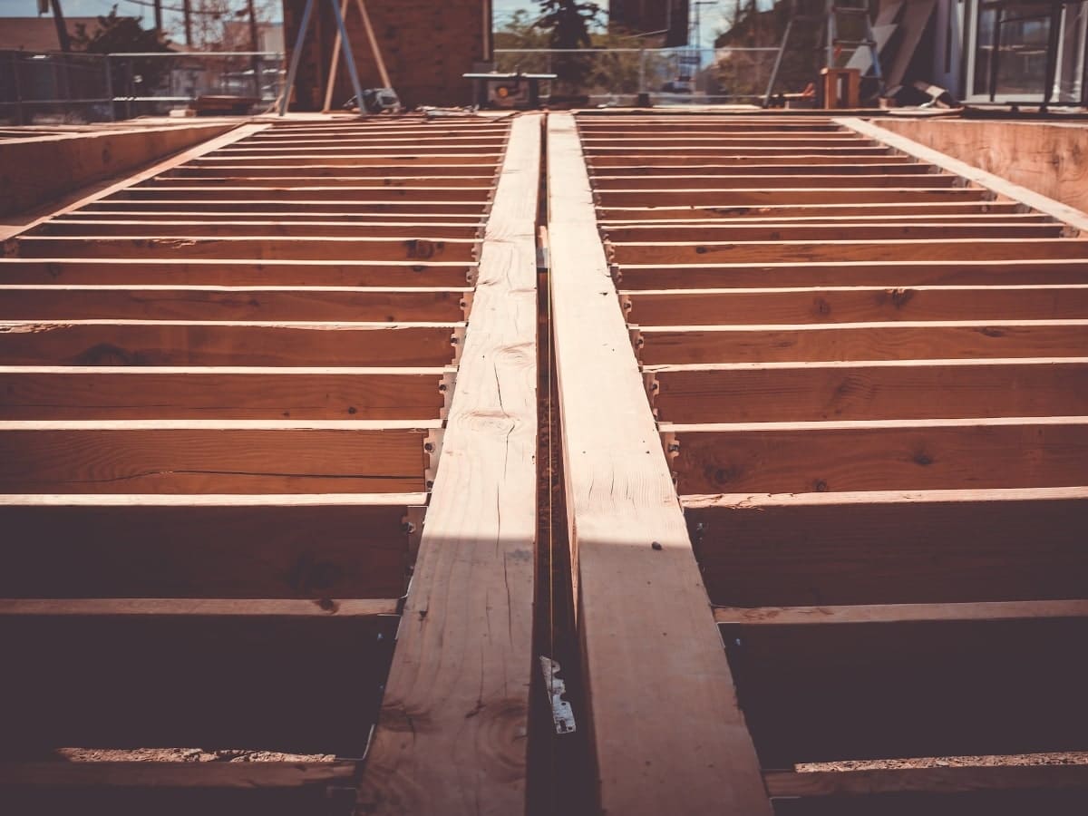 View of the initial framing stage of house construction, showcasing the skeletal structure and floor joists as the foundation of the home takes shape.