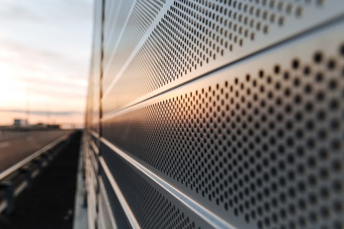 Close-up of perforated metal fencing for privacy and noise reduction.