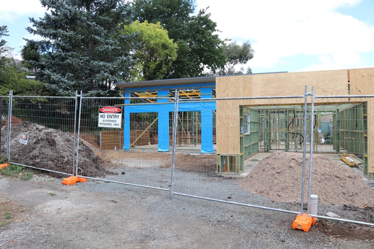 A residential home build in progress, featuring temporary privacy fencing around the construction site to ensure security and privacy.