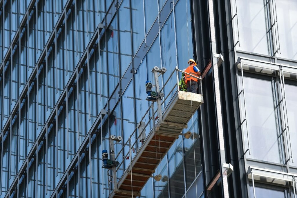 Close-up of workers using suspended scaffolding to perform maintenance on the facade of a high-rise building.