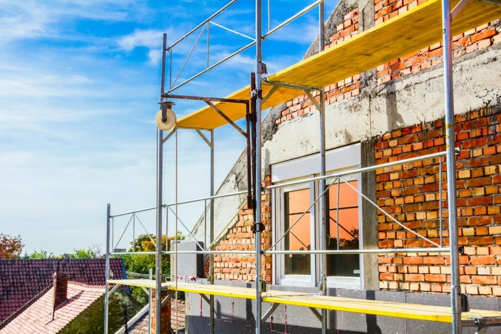 Double scaffolding system set up beside a partially restored brick building, providing enhanced stability for masonry work.