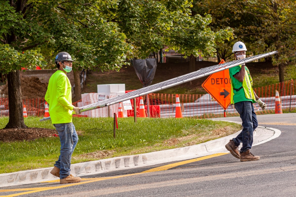 Workers carrying temporary fencing on an incline, on a construction site in Australia.