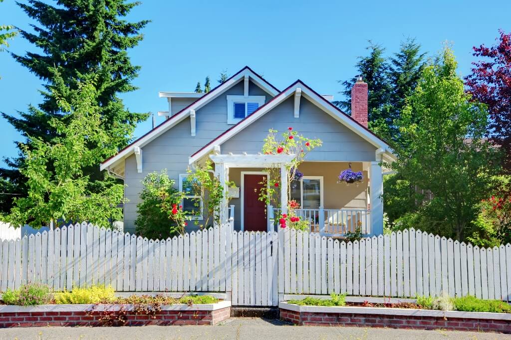 Classic-looking house with colourful rose bushes and a white picket fence