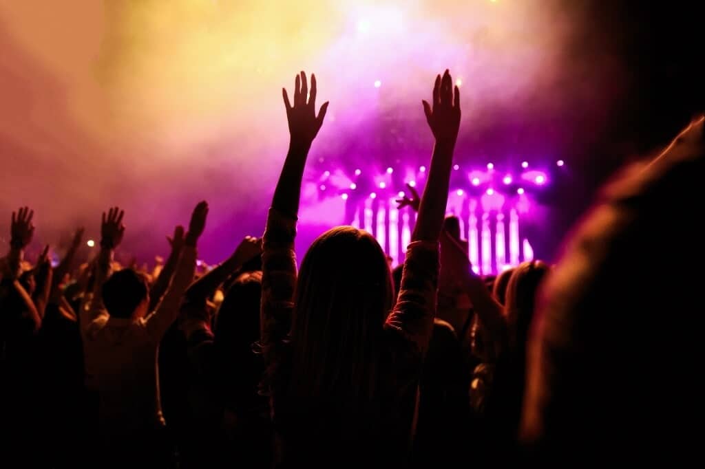 Music event crowd showing hands in the air and lights from the stage.