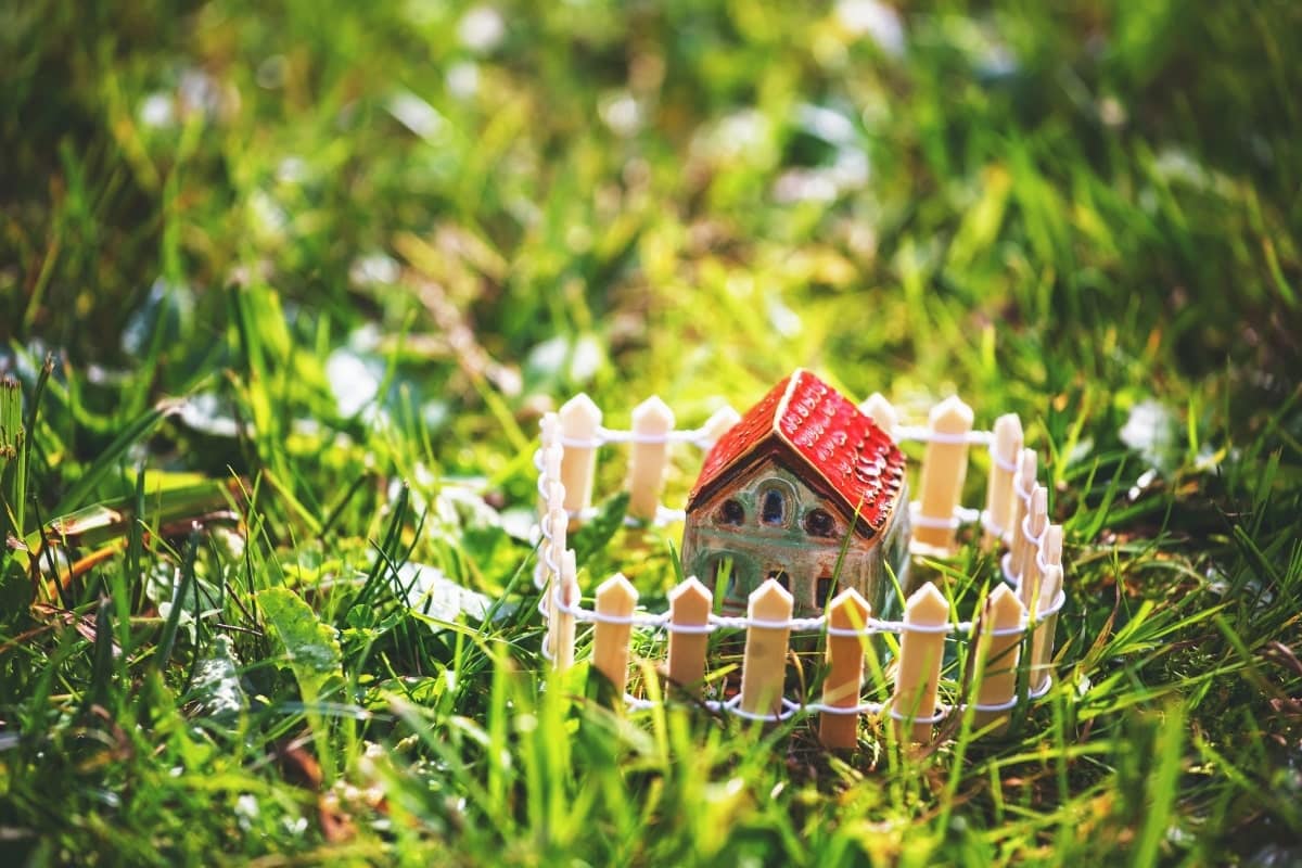 Model home placed within a temporary fence on green grass, visually depicting the ease of installing and removing fencing for renters.